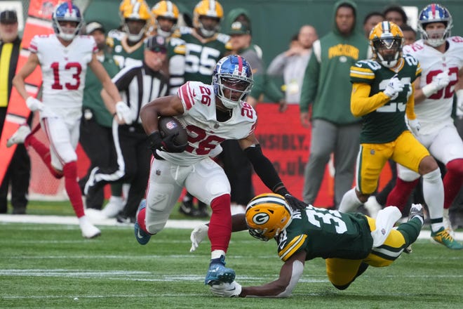 New York Giants running back Saquon Barkley (26) carries the ball in the second quarter as Green Bay Packers safety Adrian Amos (31) defends during an NFL International Series game at Tottenham Hotspur Stadium.