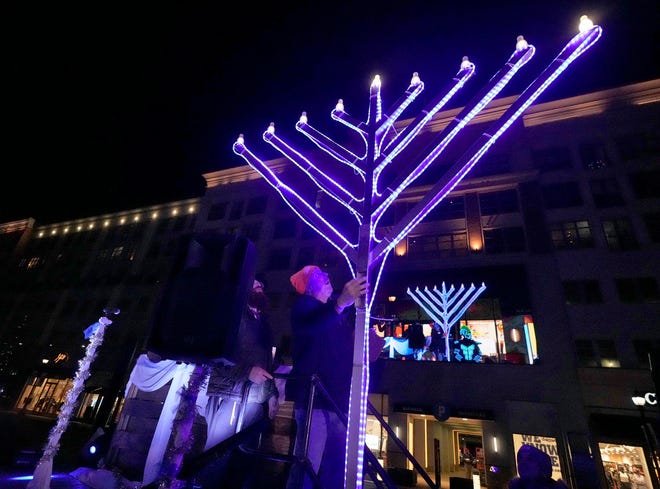 Glendale Mayor Bryan Kennedy flips the switch to light the menorah as part of a Chanukah Festival and Gelt Drop, to kick off the first day of Chanukah, in The Yard at Bayshore in Glendale on Thursday, Dec. 7, 2023. The largest Hanukkah festival in Wisconsin, hosted by Lubavitch of Wisconsin, included live music, a giant Menorah lighting, and a mega gelt and gift drop.