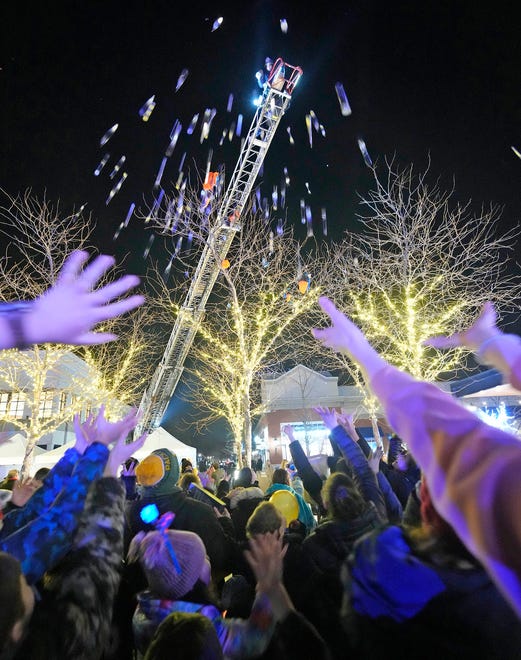 A Northshore firefighter tosses gelt, or chocolate coins from a ladder truck as part of a Chanukah Festival and Gelt Drop, to kick off the first day of Chanukah, in The Yard at Bayshore in Glendale on Thursday, Dec. 7, 2023. The largest Hanukkah festival in Wisconsin, hosted by Lubavitch of Wisconsin, included live music, a giant Menorah lighting, and a mega gelt and gift drop.