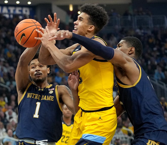 Marquette forward Oso Ighodaro (13) drives past Notre Dame guard Julian Roper II (1) and forward Kebba Njie (14) during the first half of their game Saturday, December 9, 2023 at Fiserv Forum in Milwaukee, Wisconsin.